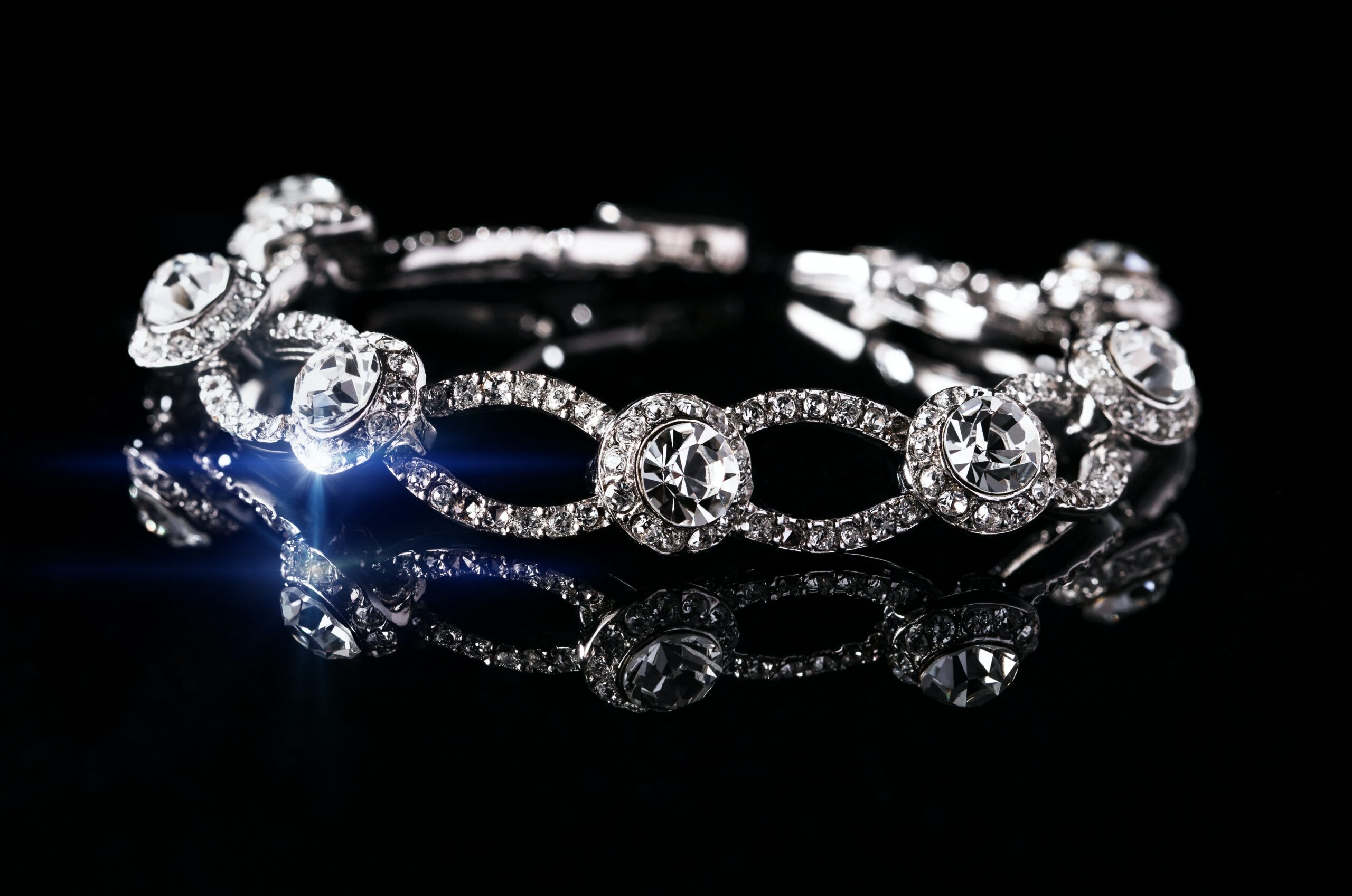 An elaborate silver and diamond ring on a reflective black surface.